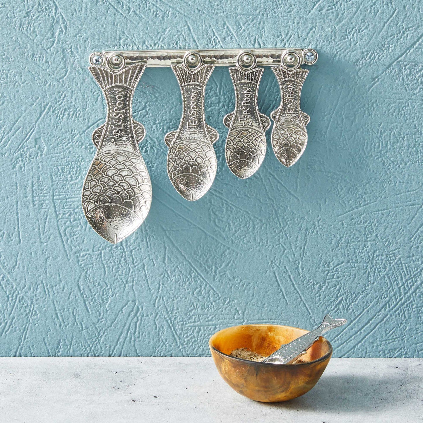 pewter fish measuring spoons on wall strip